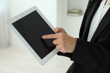 Businesswoman using tablet indoors, closeup. Modern technology