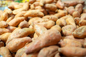 A pile of sweet potatoes on display at a grocery store