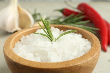 Sea salt and rosemary in bowl on table, closeup
