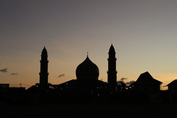 silhouette of the mosque at sunset. A religious structure at sunset, framed by trees and the sky.