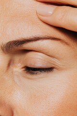 Obraz premium A high-resolution image of a woman applying anti-aging cream to her forehead to reduce wrinkles, with a neutral background and soft texture emphasizing her face and skincare.