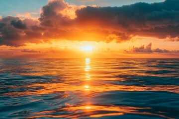 Obraz premium Orange sunset reflected in calm ocean water.