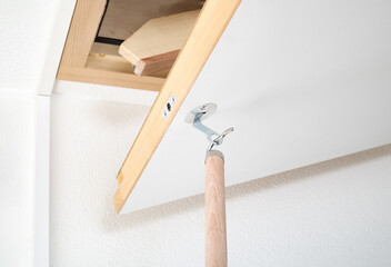 Attic hatch or loft door is opened with handle. Loft sliding ladder with open hatch or attic door....