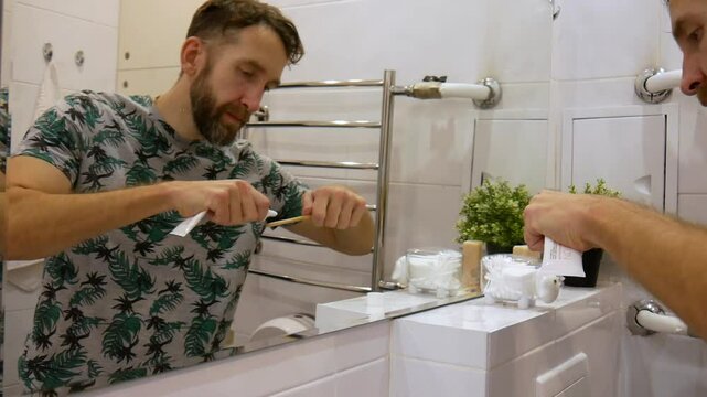 A man brushing his teeth in front of a bathroom mirror