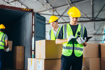 Three warehouse workers using a digital tablet while recording inventory. Logistics employees working with warehouse management software in a large distribution centre.