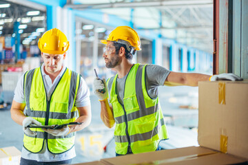 Three warehouse workers using a digital tablet while recording inventory. Logistics employees working with warehouse management software in a large distribution centre.