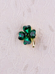 Close-up bright green beautiful clover brooch in crystals on light background