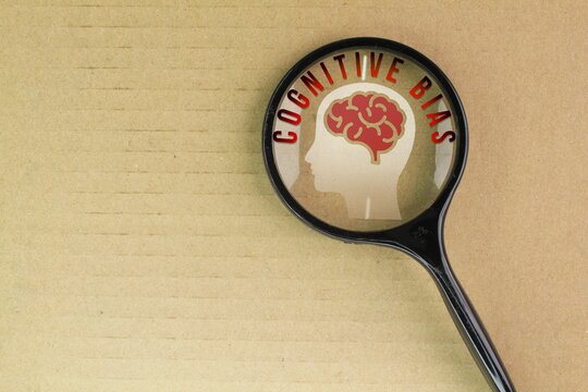 magnifying glass with brain icon and the word Cognitive bias. systematic patterns of deviation from norm or rationality in judgment