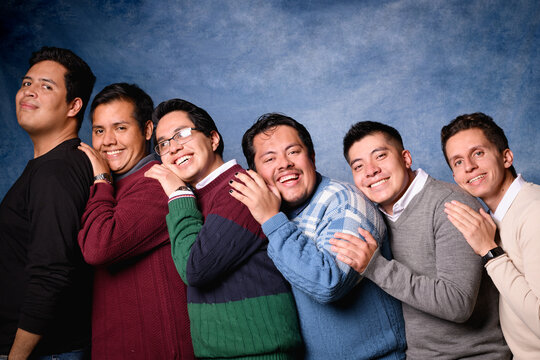Group of 6 men in sweater on blue background in 90's yearbook style. Posing in a romantic way