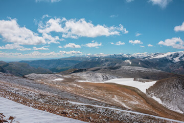 Snowy stony pass, large colorful mountain range and valley in far away. Snow-white glacier in...