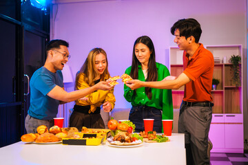 Four Asian friends, two men and two women, celebrate in an office party. They enjoy a fun-filled night with food, drinks, and laughter, bonding over teamwork and friendship.