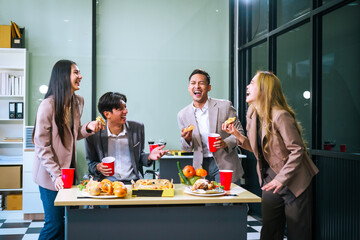 Four Asian friends, two men and two women, celebrate in an office party. They enjoy a fun-filled with food, drinks, and laughter, bonding over teamwork and friendship.