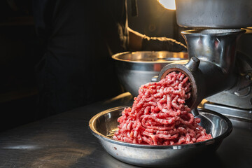 chef grinding meat in the kitchen with modern electric grinder