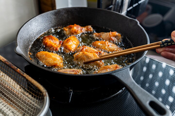 chicken wing fried until golden brown in bubbling hot vegetable oil, home cooking concept