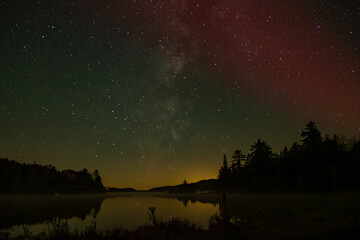Naklejka premium Slight Aurora Borealis, Northern lights and the Milky Way at night with lake reflection