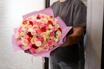 delivery man delivers a bouquet of beautiful flowers to home. 