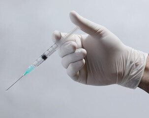 doctor in a medical mask with a syringe on a black background.