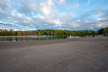 Green Lakes State Park in Syracuse offers a peaceful view of its crystal-clear waters, framed by lush trees. The sunset glow casts a soft light on the serene lake, making it a perfect spot for reflect