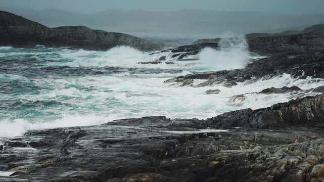 Turbulent waves crash onto the rocky shore, highlighting the wild and rugged terrain of the Atlantic Road coast.
