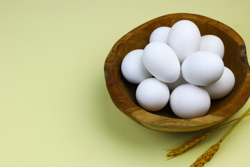 Raw Eggs from white leghorn chicken on wooden bowl. Selective focus with isolated background and copy space.