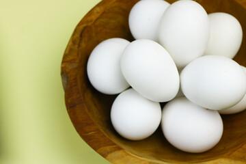 Raw Eggs from white leghorn chicken on wooden bowl. Selective focus with isolated background and copy space.