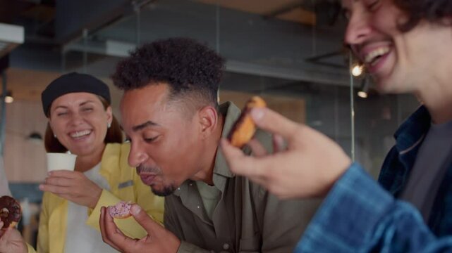 Positive group of co-workers enjoys lunchtime eating snacks