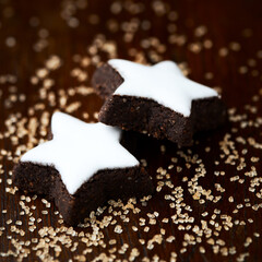 Christmas cookies (cinnamon stars) and brown sugar on dark background. Close up.	