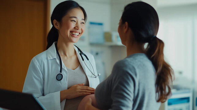 女性の医師と会話するアジア系の妊婦の画像