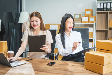 Two Asian business woman work at desk, selling fashion clothes online. They are packing checking items, ready to send to customers. Their clear business planning ensures success in sales marketing
