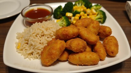 a plate with rice, broccoli and nuggets in close-up