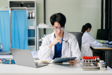 Doctor analyzing patient data on tablet in clinical lab. Medical professional in hospital with laptop, blood samples