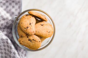 Biscotti frollini con gocce di cioccolato. Chocolate cookies in bowl on kitchen table. Top view.