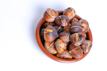 fresh seasonal chestnuts roasted in an earthenware bowl isolated on a white background and copy space