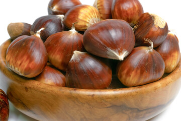 fresh seasonal chestnuts harvested in the field in a wooden bowl isolated on a white background and copy space