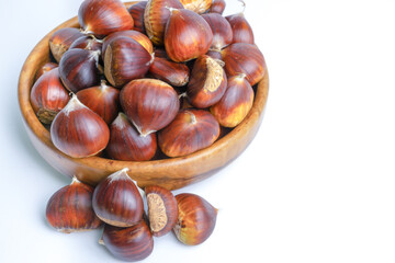 fresh seasonal chestnuts harvested in the field in a wooden bowl isolated on a white background and copy space