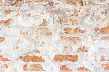 Empty Old Brick Wall Texture. Painted Distressed Wall Surface. Grungy Wide Brick wall. The texture of a very old vintage brick wall with residual elements of plaster decoration.