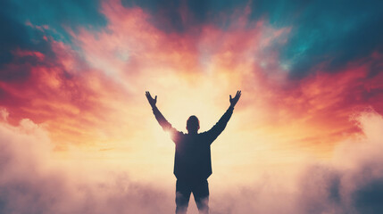 Fototapeta premium Silhouette of a man with arms raised against a dramatic sunset.