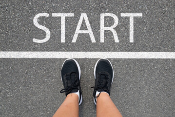 New year 2025, motivation for a new start, the concept of starting a business. A woman in sneakers stands on an asphalt road at the start line.