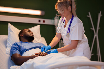In the patient's room, the assistant doctor ensures the catheter for the IV drip is properly in...