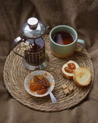 Teapot, cup of tea and baguette with apricot jam