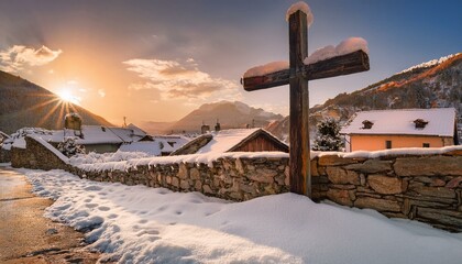 A large wooden cross, partially covered in snow, leaning against a stone wall in a peaceful village as the sun sets behind the mountains.