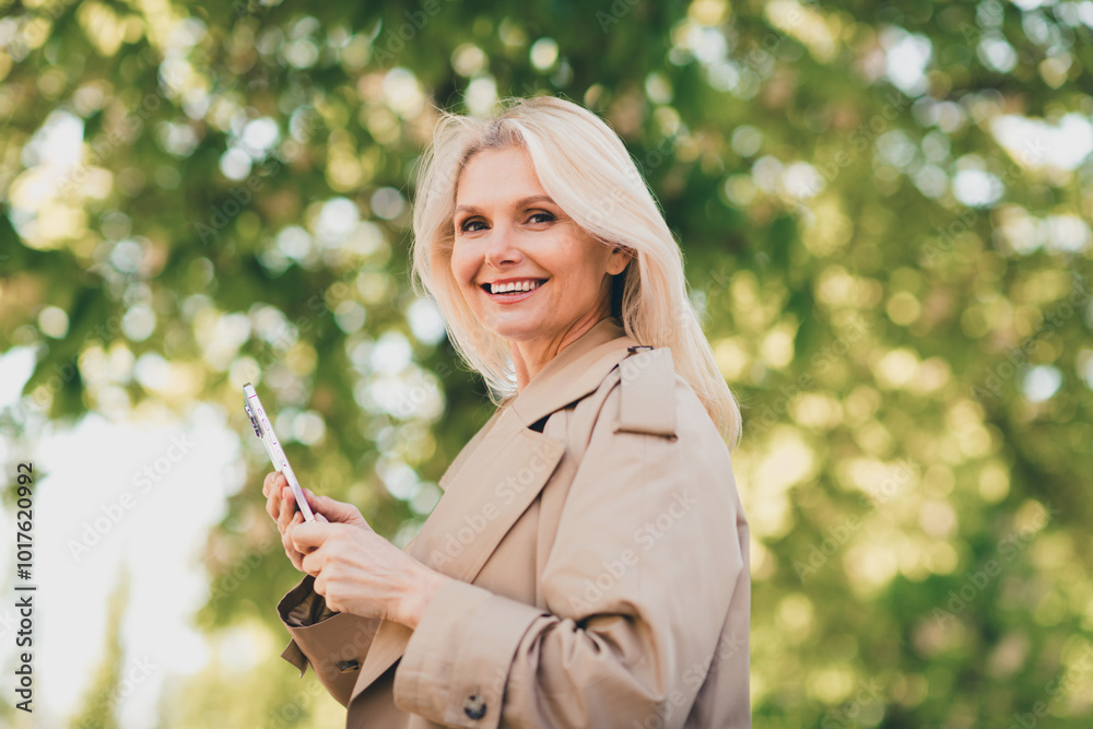 Canvas Prints Portrait of positive cheerful happy retired woman smile spring good mood hold device weekend wear beige coat outdoors outside park street