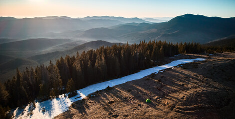 Beautiful panorama of sunny day in mountains with rocky hills, coniferous forest and snow