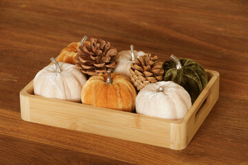 Wooden box with pumpkins, light beige plaid, orange velvet pillow and boho pillow with fringe lying...