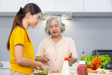 Senior asian mother and middle aged daughter cooking together at kitchen