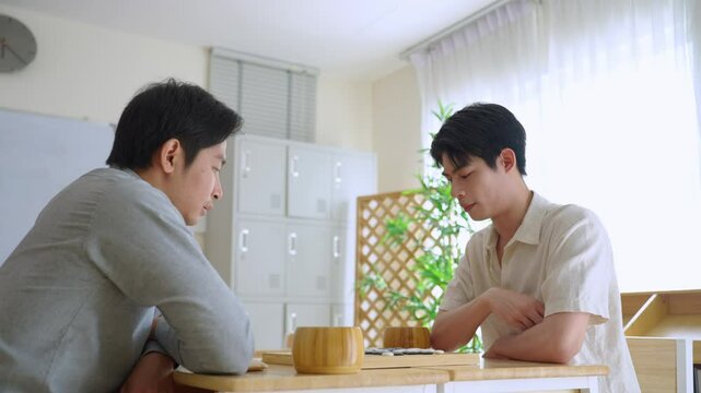 Asian young men playing board game Go during competition in community.