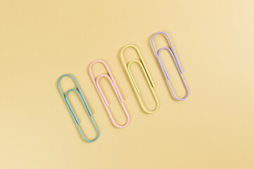 Top view of colorful paperclips on yellow background. School, office wallpaper. Flat lay, copy space.