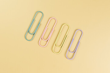 Top view of colorful paperclips on yellow background. School, office wallpaper. Flat lay, copy space.