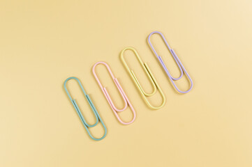 Top view of colorful paperclips on yellow background. School, office wallpaper. Flat lay, copy space.
