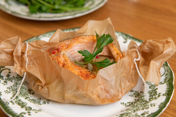 Salmon fillet seasoned with herbs and spices baking in parchment paper on a plate